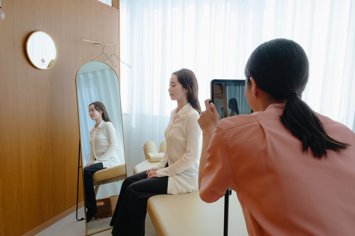 座った患者様の姿勢をタブレットで撮影する女性のセラピスト