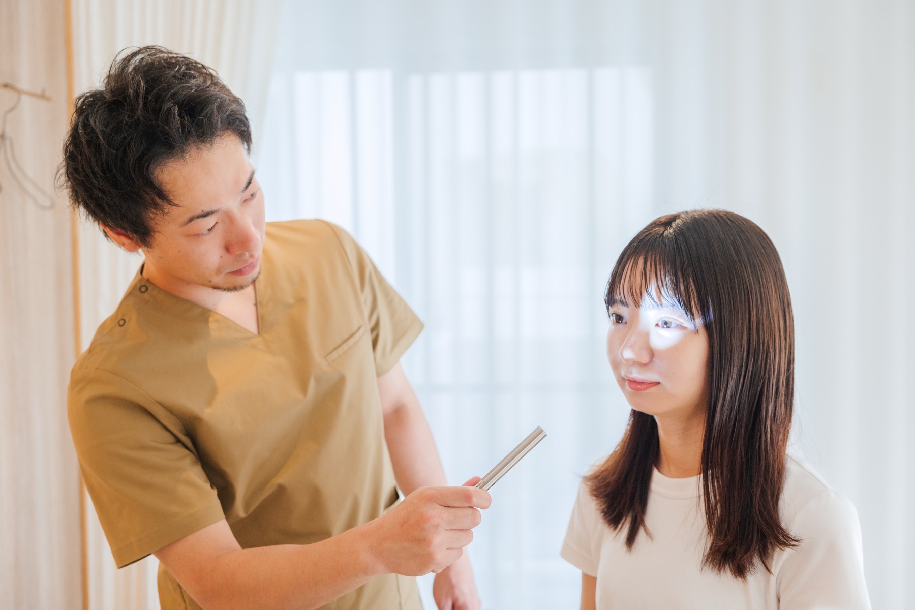 セラピストがペンライトで患者様の目の反応を確かめている様子